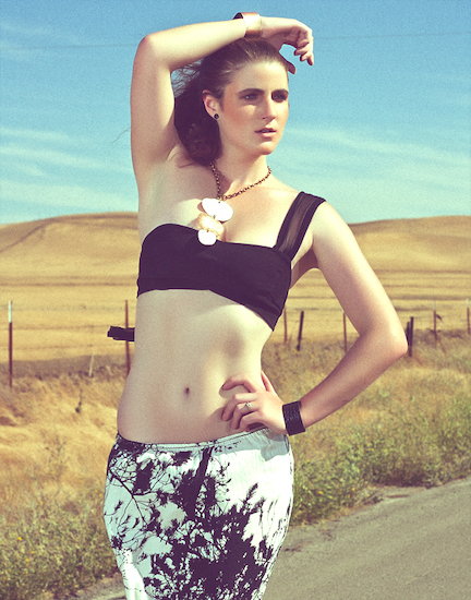 Bright blue sky over a golden feild, wearing black and white tie dye pants and a crop top with metal jewlery